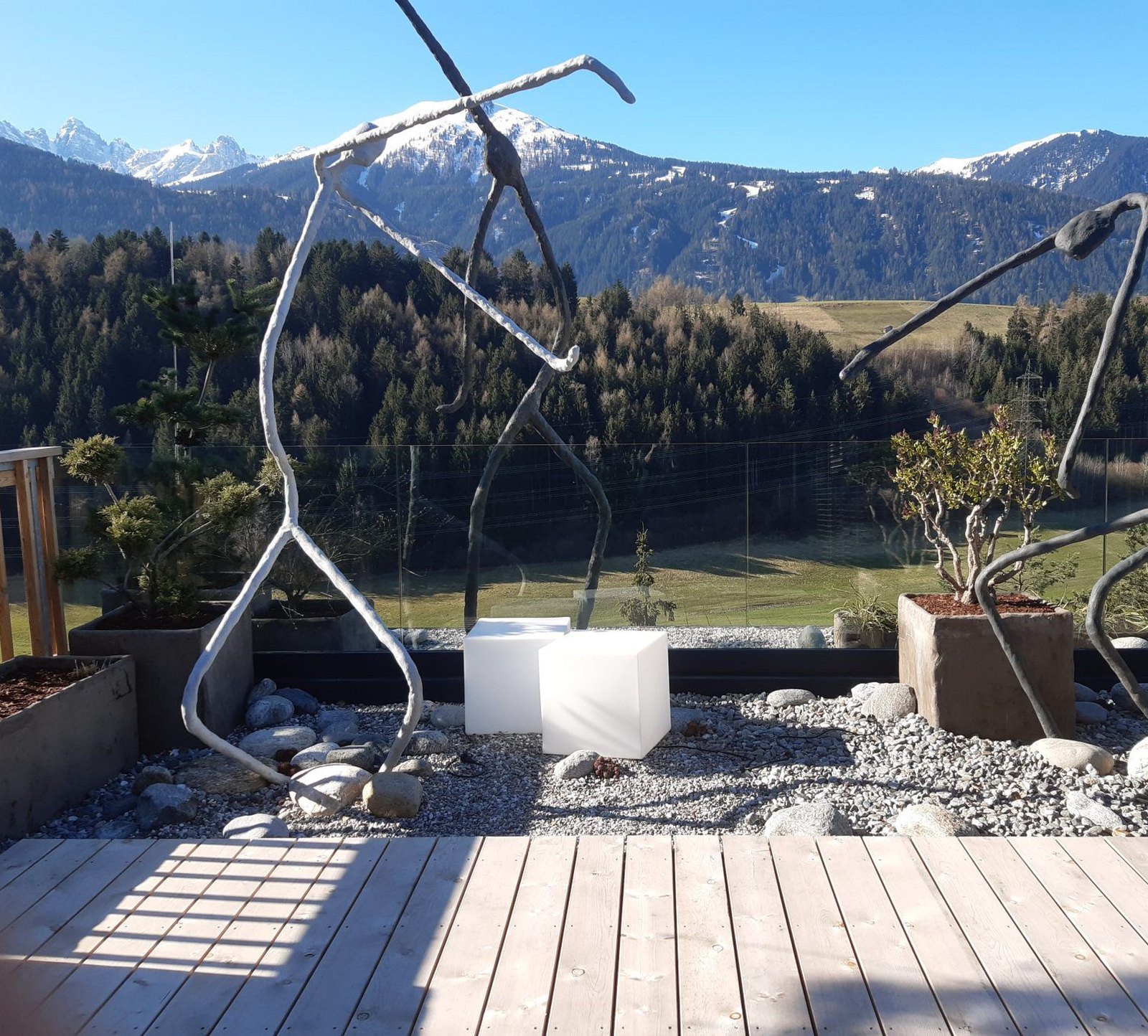 Vogelfigur und Skulpturen auf der Terrasse vor Bergkulisse