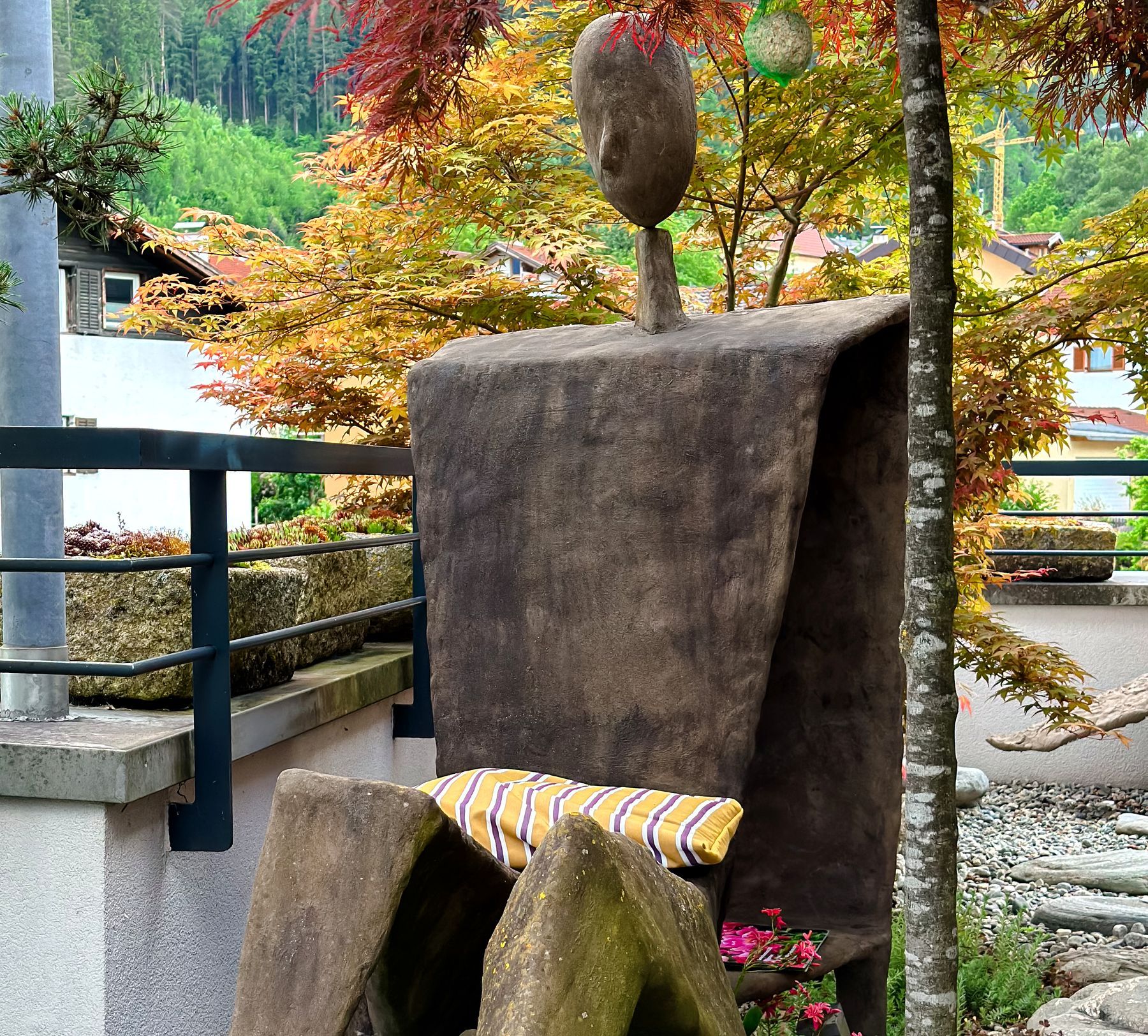 Objektkunst: Sitzende Figur im Garten